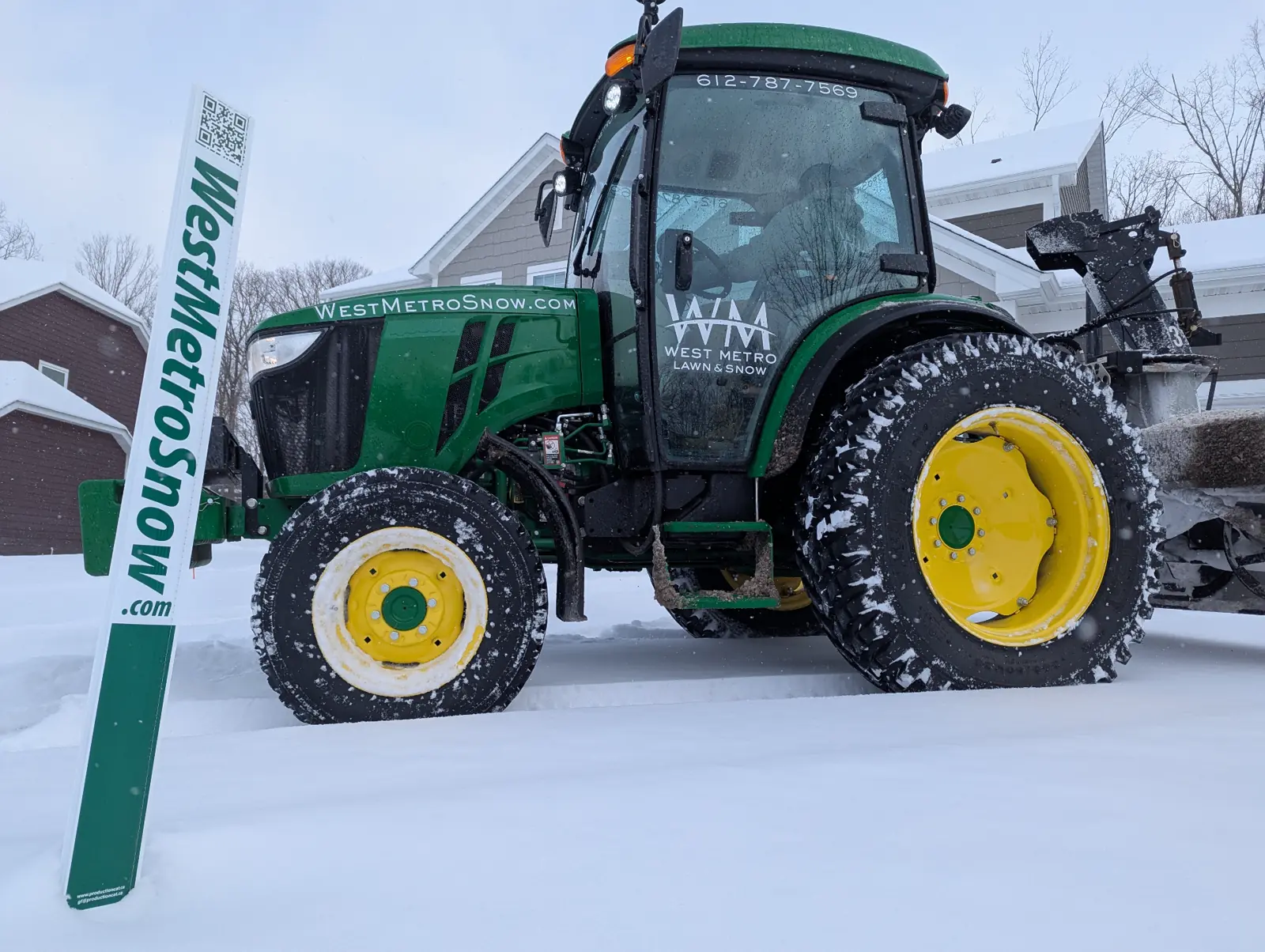 West Metro Lawn & Snow branded tractor with snow stakes in a residential neighborhood