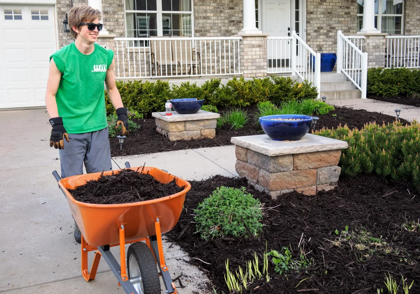 A West Metro Lawn & Snow crew member installing fresh mulch in a landscape bed at a west metro home